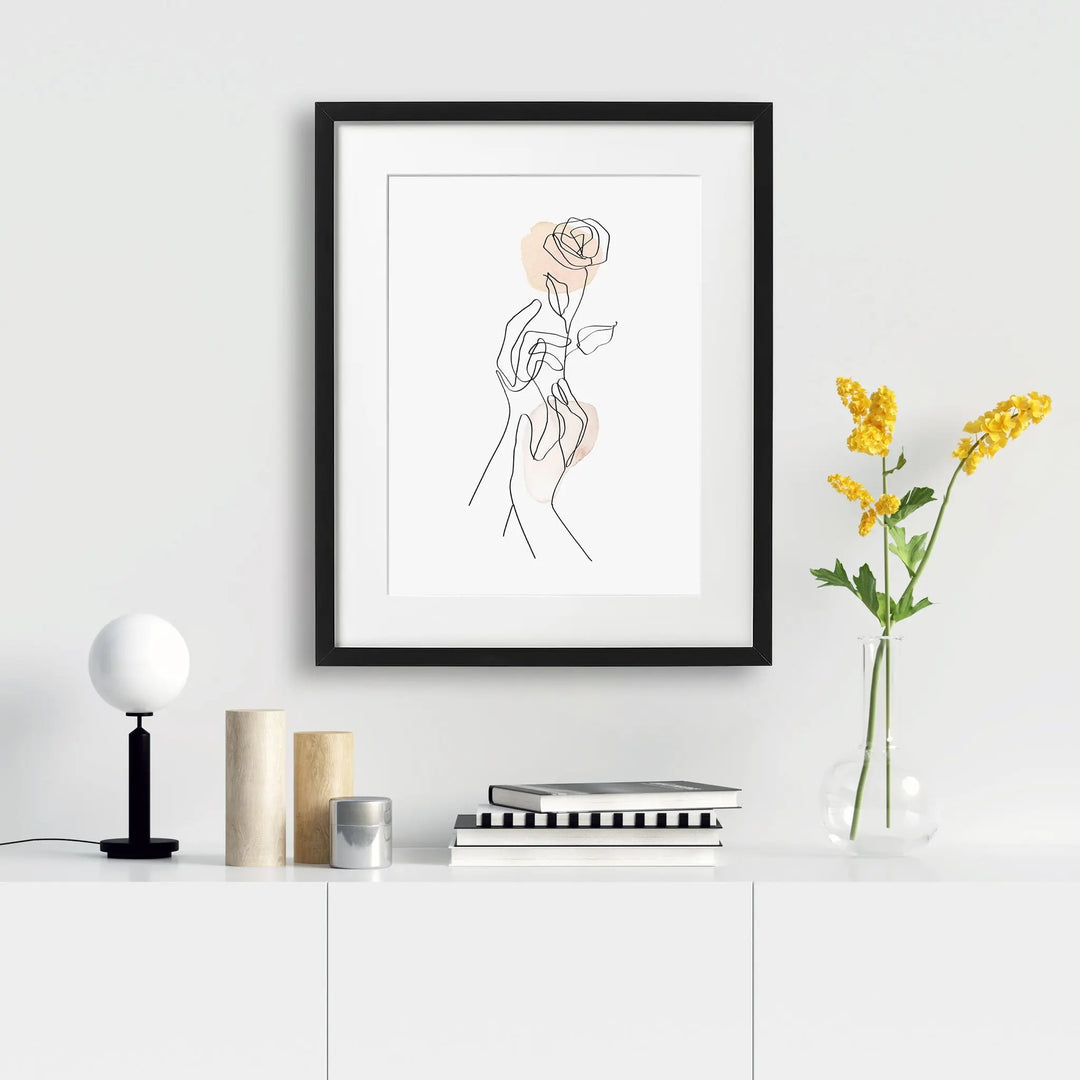 Tabloul cu rama care ilustreaza un desen line art simplu si elegant cu 2 maini tinand un trandafir gentle gesture
